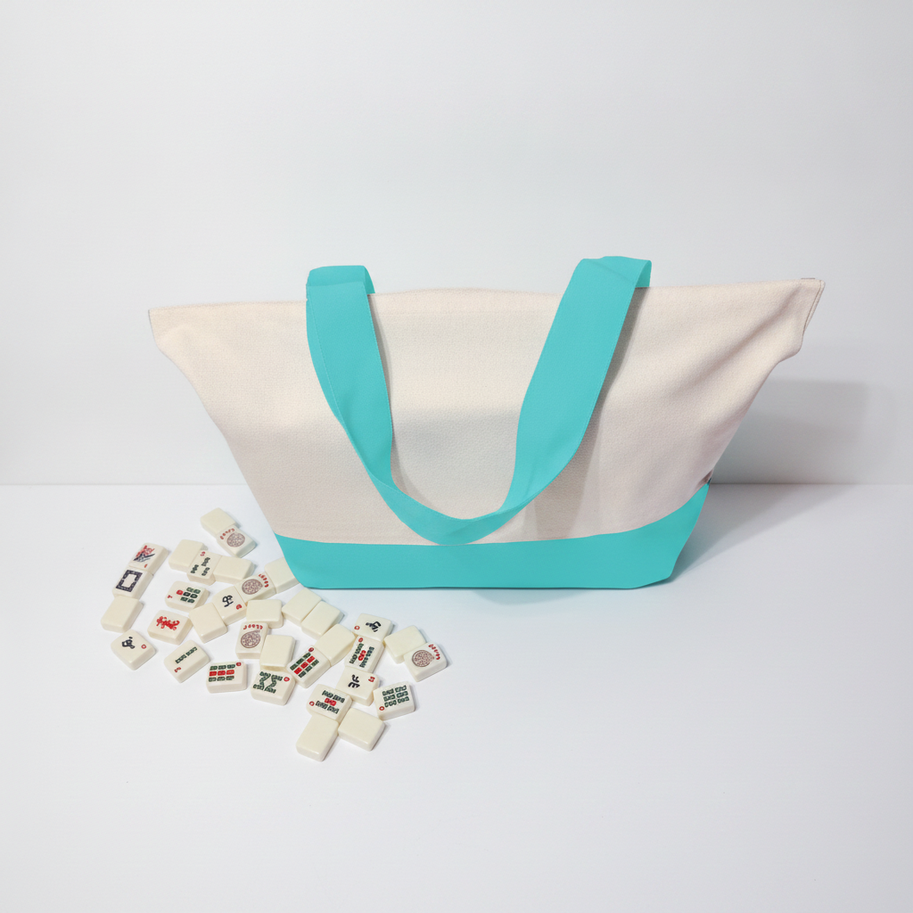 An off-white canvas tote bag with bright turquoise blue handles, base trim, and a matching turquoise arch detail across the front. Several small white game pieces with multicolored symbols are scattered in front of the bag on a clean white studio background.